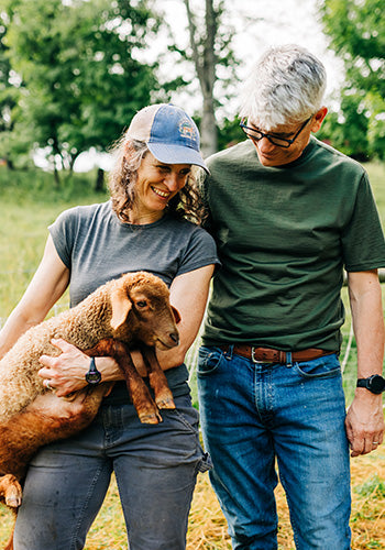 couple in lightweight merino wool t shirts holding a lamb