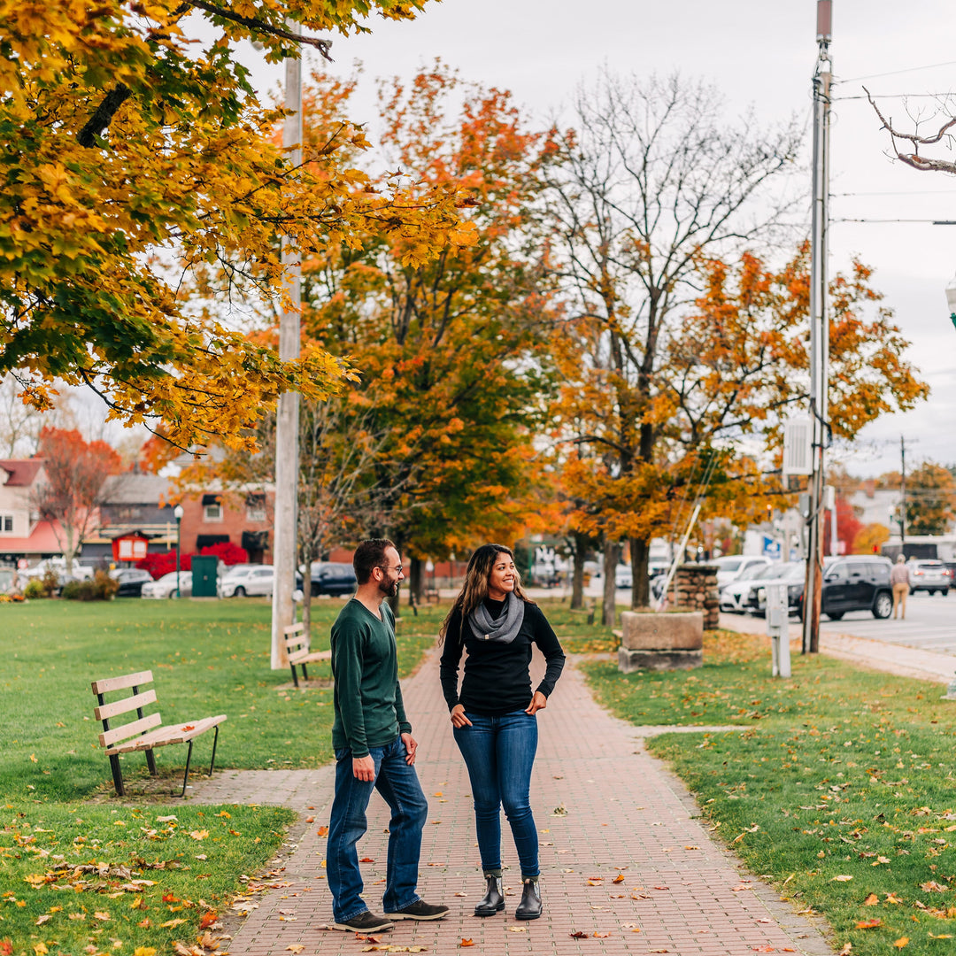 A man and a woman standing on a side walk talking to each other. 