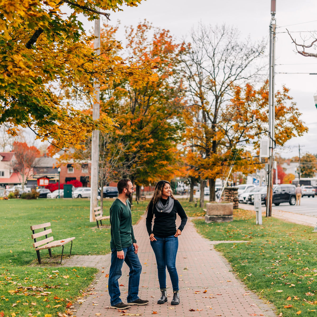 A man and a woman standing on a side walk talking to each other. 