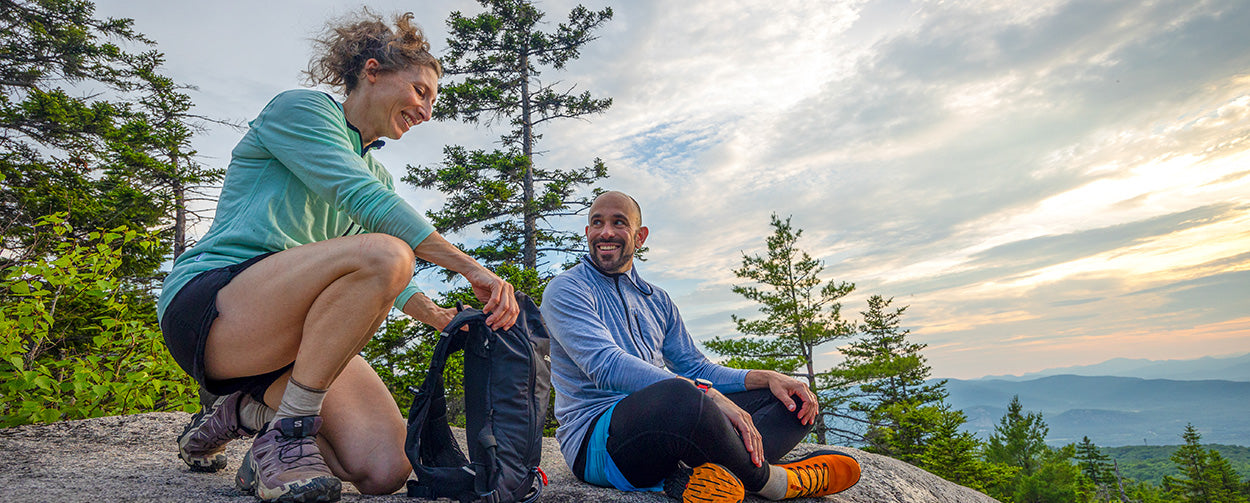 People hiking wearing merino wool sunhoodies. A man and woman talking at the top of the summit