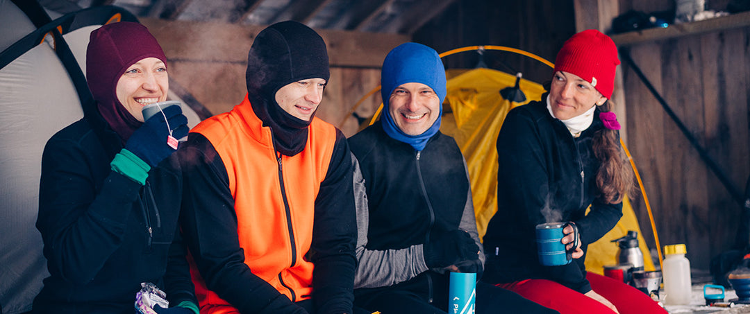 group of people winter camping sitting wearing merino wool accessories
