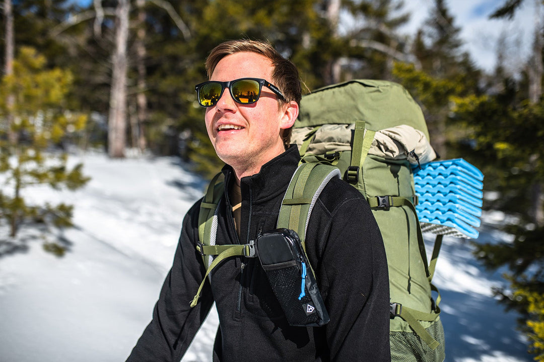 man and woman snowshoeing while wearing minus33 merino wool beanie, jacket, gloves and  base layers