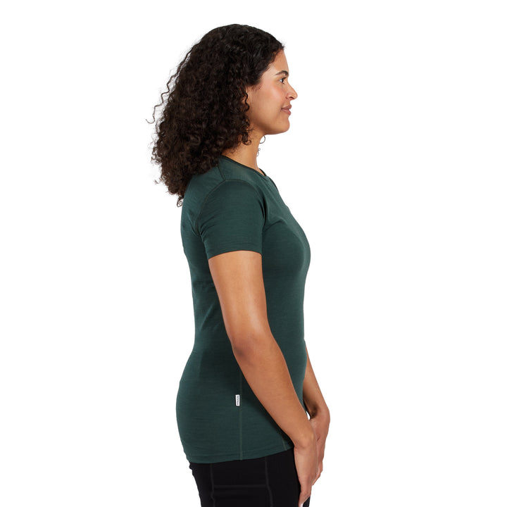 A woman with curly dark hair is shown in profile wearing a dark green short-sleeve athletic top and black pants against a plain white background. 