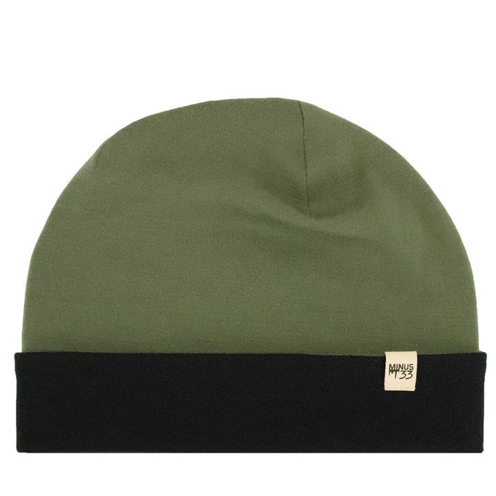 An olive green beanie hat with a black folded cuff and a small beige brand tag on the side, shown against a plain white background. 