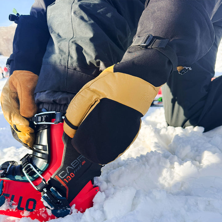 ski boot in the snow wearing yellow and black waterproof winter ski gloves #color_tan