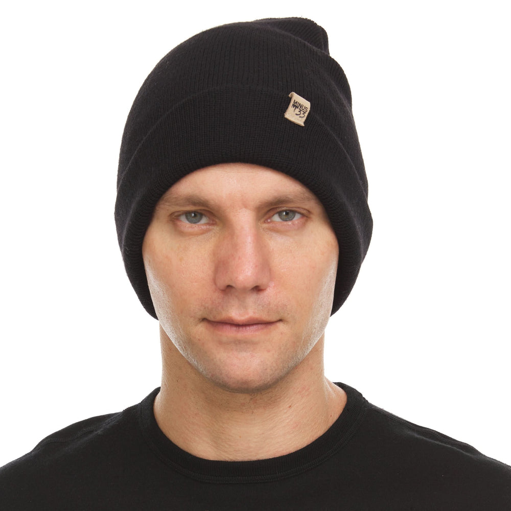 A man models the midweight double-layered merino wool beanie, front three-quarter view #color_black