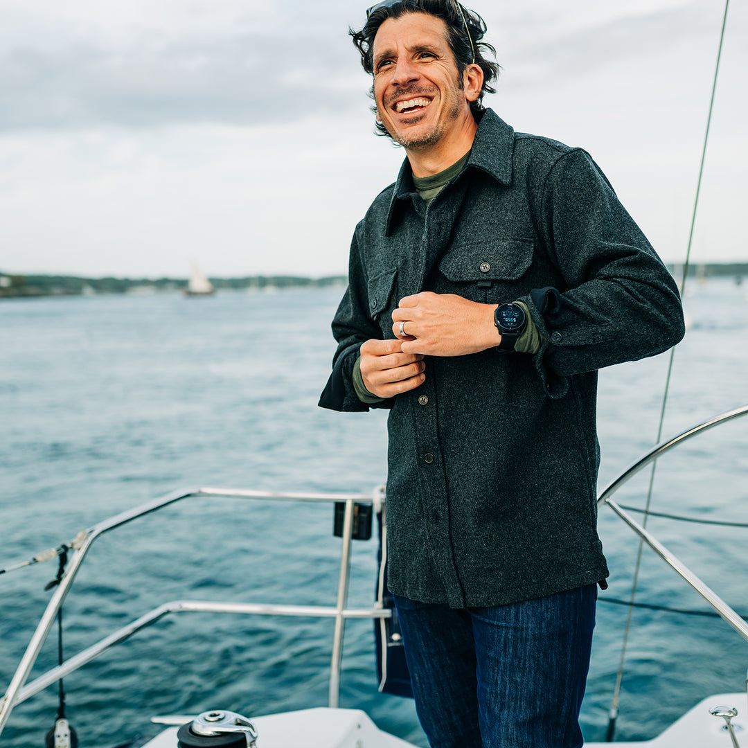 Man buttons heavy wool shirt jac while sailing #color_charcoal-gray