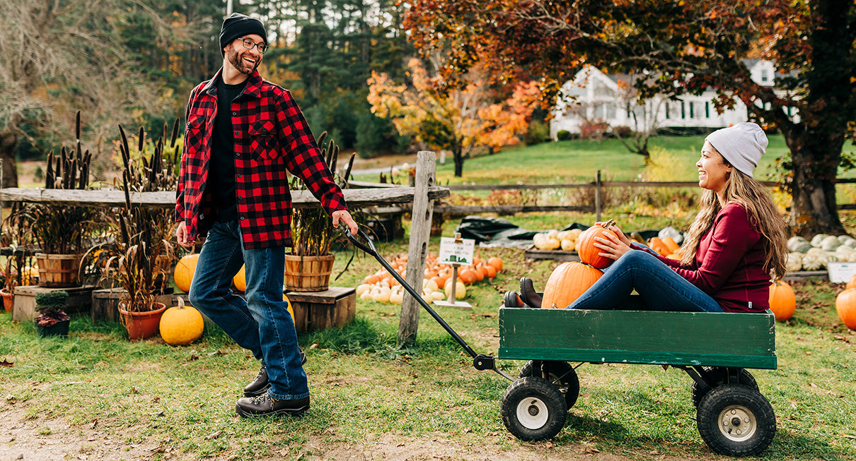 couple picking pumpkins wearing midweight merino wool clothing and beanies