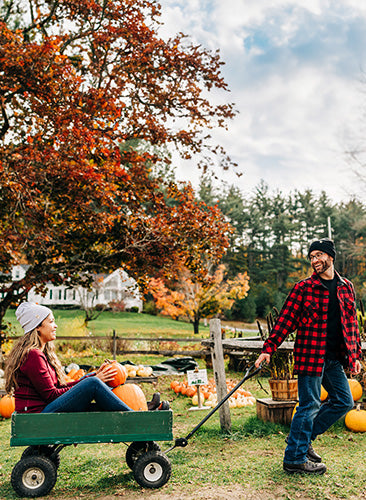 couple picking pumpkins wearing midweight merino wool clothing and beanies