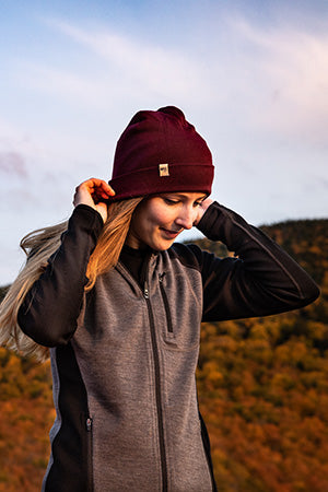 women putting on midweight beanie wearing midweight woolverino full zip hoodie